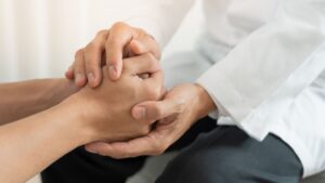 Psicóloga sosteniendo las manos de su paciente