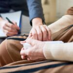 Psicóloga sosteniendo las manos de su paciente